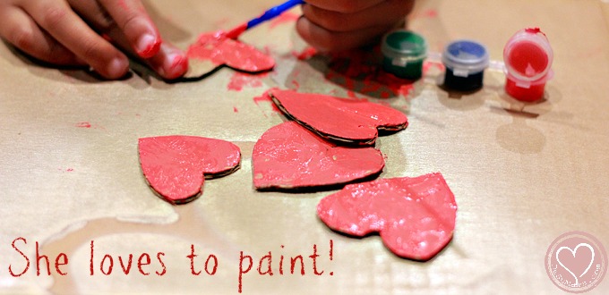 toddler painting, red hearts being painted by little girl